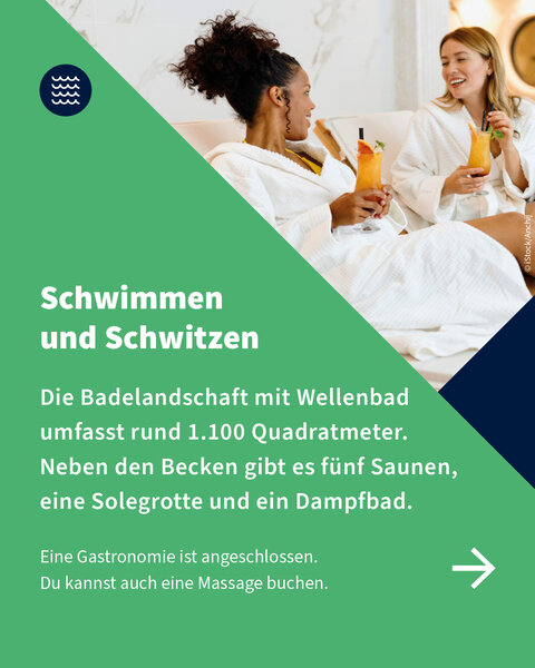Zwei Frauen in weißen Bademänteln sitzen in der Therme, lachen und trinken bunte Cocktails – Wohlfühlmoment nach dem Schwimmen oder Saunieren.